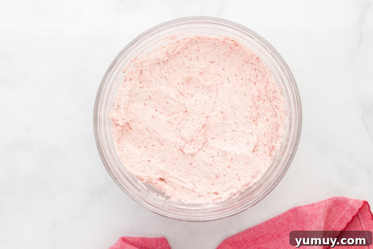 strawberry icing in a glass bowl with a pink towel.
