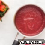 strawberry sauce in a pan next to strawberries.
