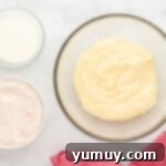 a bowl of flour, eggs and milk on a marble table.