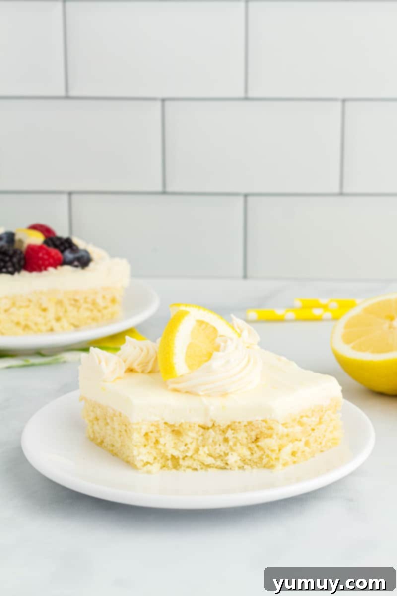 Sunshine Lemon Sheet Cake 2 a slice of lemon sheet cake on a white plate, garnished with fresh berries and lemon zest.