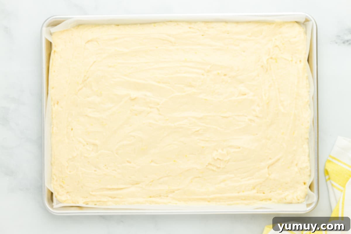 Sunshine Lemon Sheet Cake 11 Delicious lemon cake batter smoothly spread across a sheet pan, ready to be baked to golden perfection.