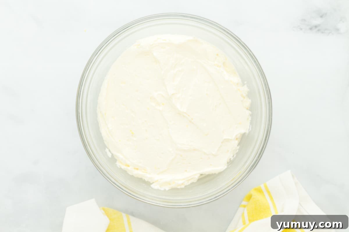 Sunshine Lemon Sheet Cake 13 Decadent lemon buttercream frosting in a deep mixing bowl, exhibiting its fluffy texture and ready for spreading.