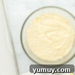 Sunshine Lemon Sheet Cake 5 lemon cake batter in a glass bowl on a marble countertop, showing its smooth consistency.