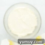 Sunshine Lemon Sheet Cake 8 creamy lemon buttercream frosting in a glass mixing bowl, light and fluffy.