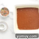 a bowl of chocolate cake with sprinkles and a whisk.