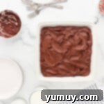 chocolate cake in a white dish with icing and sprinkles.