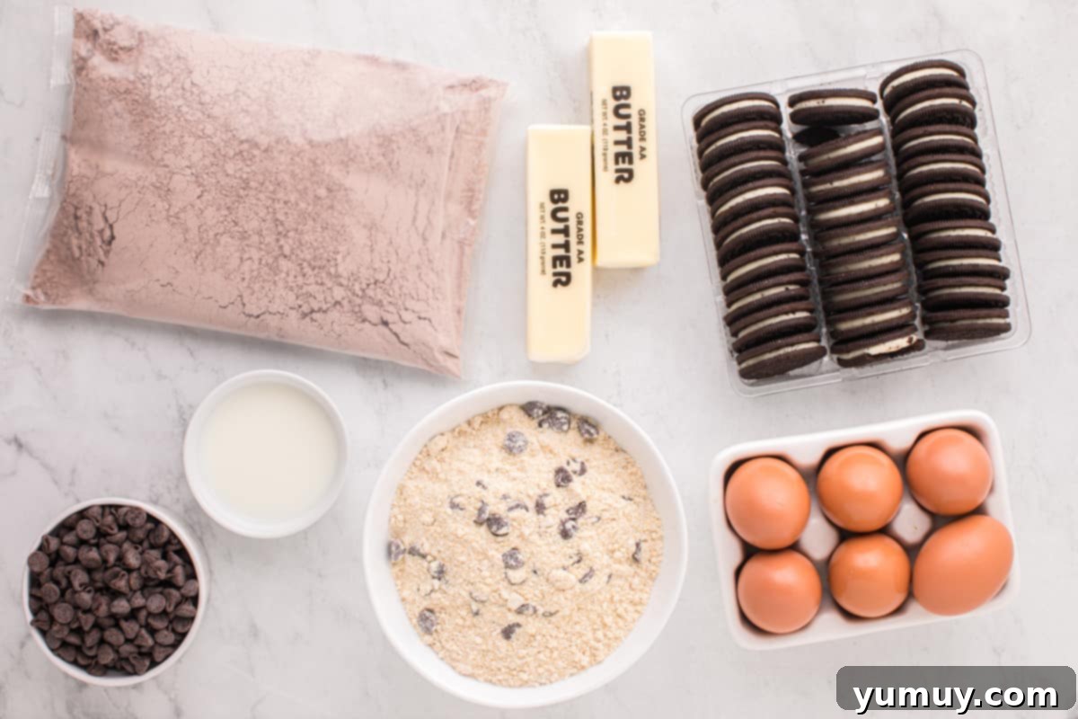 All the necessary ingredients for Slutty Brownies laid out on a marble table: cookie mix, Oreos, brownie mix, eggs, butter, milk, and chocolate chips.