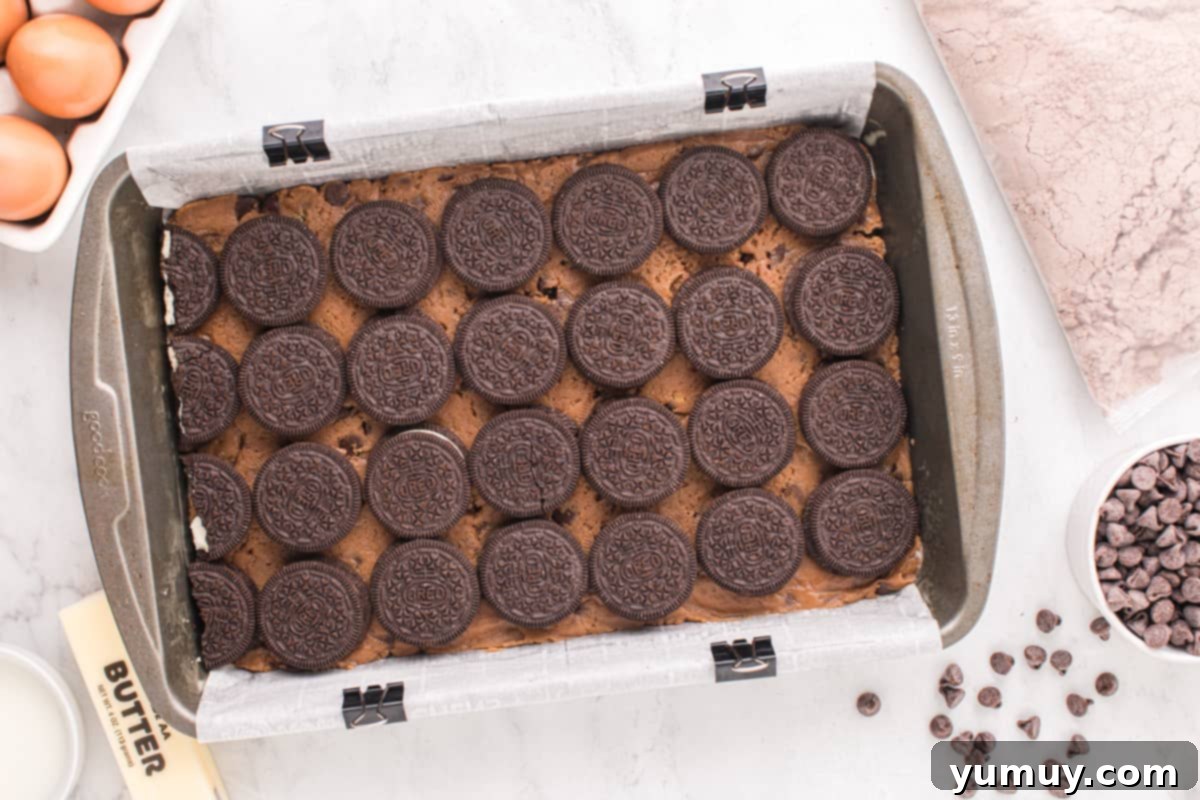 Rows of Double Stuf Oreos carefully placed over the chocolate chip cookie dough layer in a baking pan.