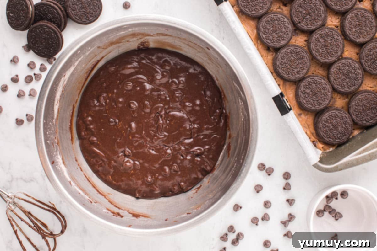 Brownie batter being mixed in a bowl with wet ingredients, achieving a smooth and pourable consistency.