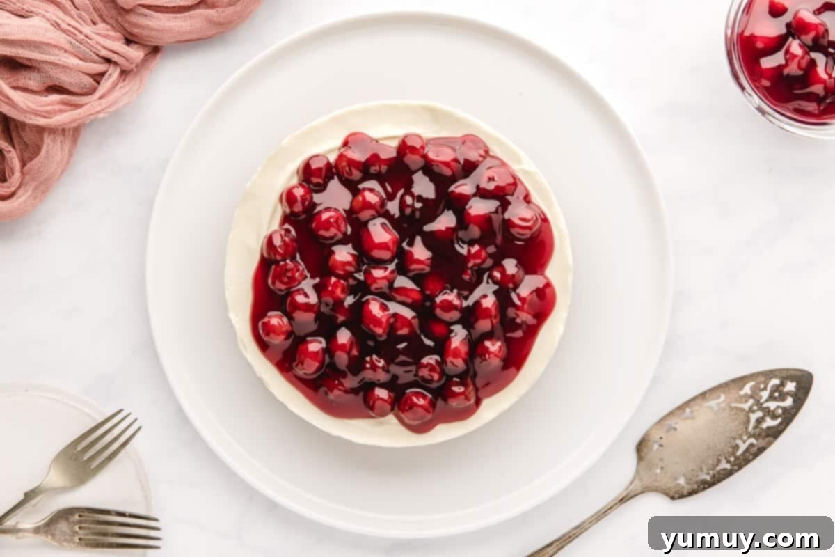 A vibrant no-bake cherry cheesecake, beautifully topped with a glistening layer of cherry pie filling, ready to be served.