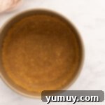 Graham cracker crust pressed into a springform pan on a marble countertop, ready for filling.