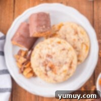 A plate of golden Butterfinger cookies alongside chocolate bars, highlighting the star ingredient.