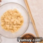 A bowl of cookie dough ready for mix-ins, with a mixing spoon nearby.
