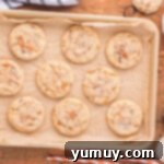 A freshly baked batch of Butterfinger cookies cooling on a baking sheet, showcasing their golden edges and crinkled tops.