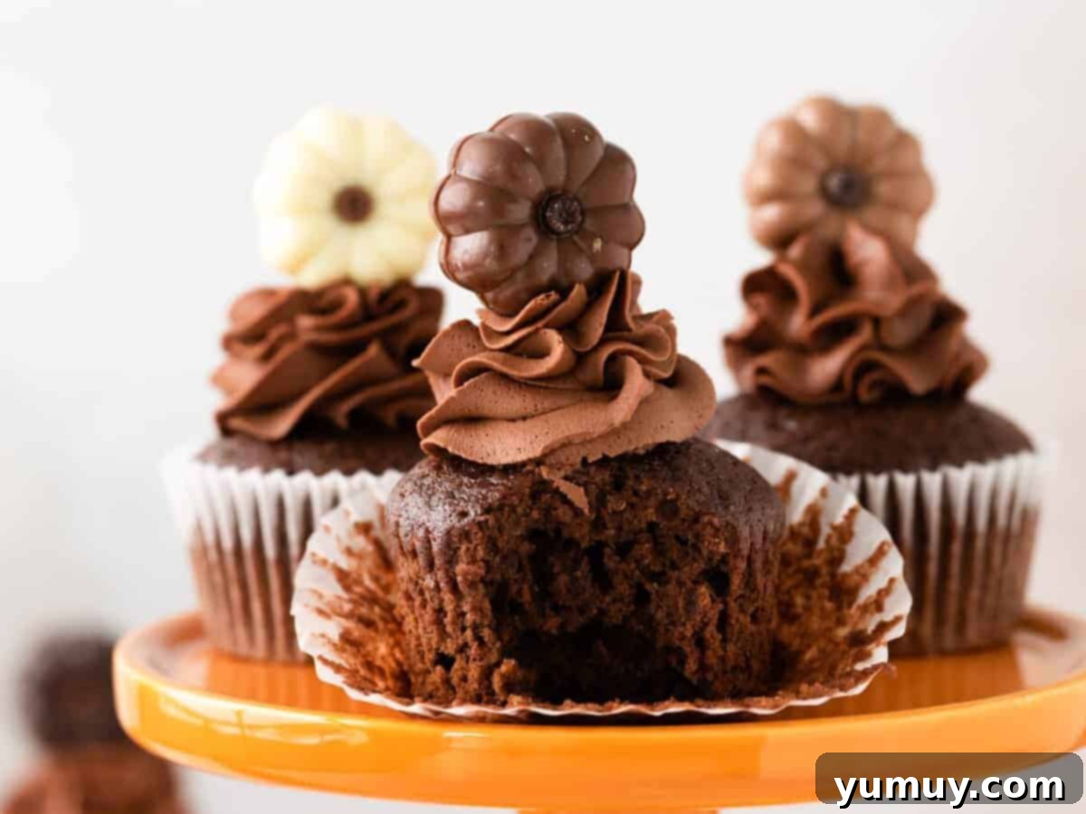 Effortless Pumpkin Puree Delights 6 3 chocolate pumpkin cupcakes and one unwrapped cupcake on an orange cake stand.