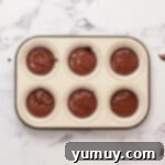 chocolate cupcake batter in the lined wells of a cupcake tin.