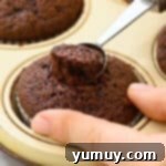 scooping out the center of a chocolate cupcake with a melon baller.