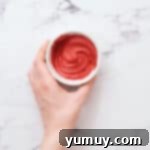 Smooth, vibrant red candy melts in a small dish, ready to be used for decorative drizzling.