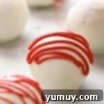 Red velvet cake truffles beautifully drizzled with melted red chocolate, resting on parchment paper and ready to harden.