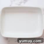 A 9x13-inch white ceramic baking pan sprayed with nonstick spray, ready for cake batter.