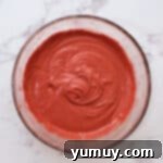 Smooth, vibrant red velvet cake batter in a large glass bowl, showing its readiness for baking.