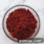 Finely crumbled red velvet cake in a glass bowl, showcasing the ideal texture for truffle making.
