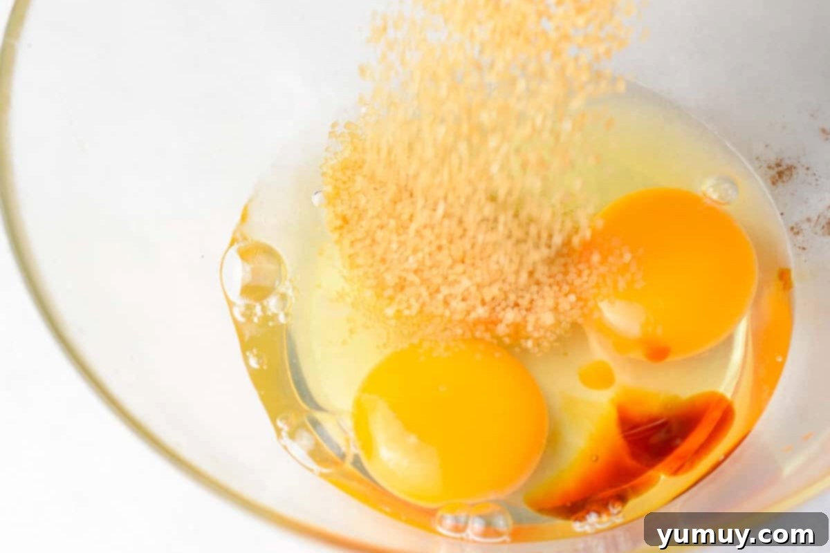 Two eggs, brown sugar, and vanilla extract are mixed in a glass bowl, ready for the next step.