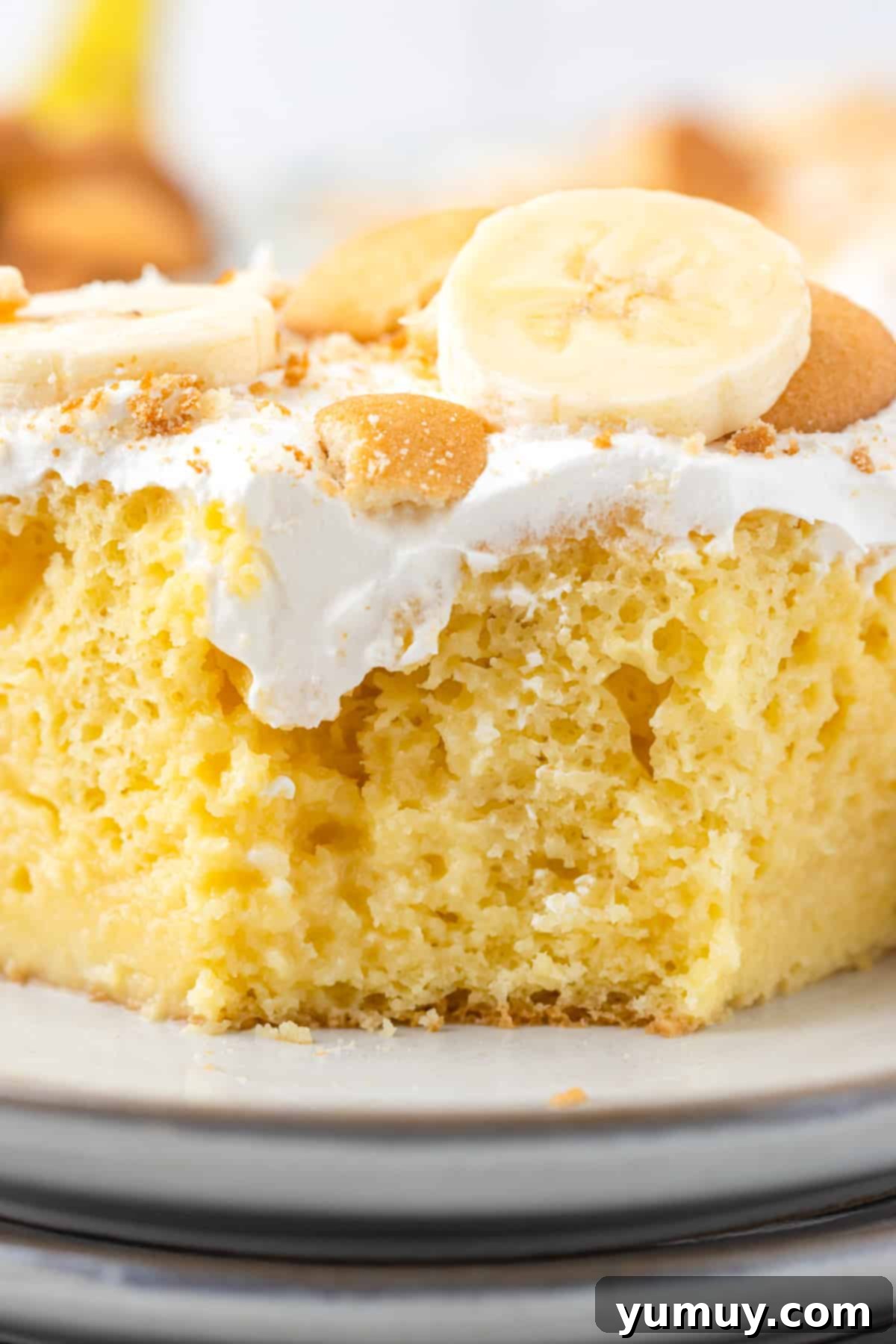 slice of banana cream pie poke cake on a white plate