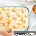 hand placing sliced bananas on top of banana cream pie poke cake
