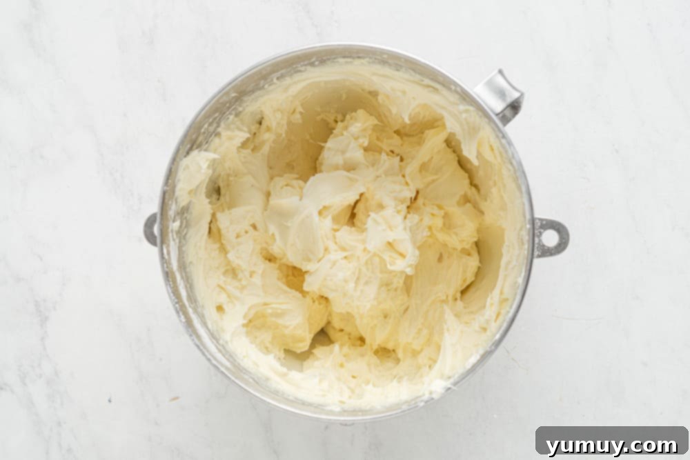 butter in a bowl on a marble countertop, alongside other frosting ingredients.