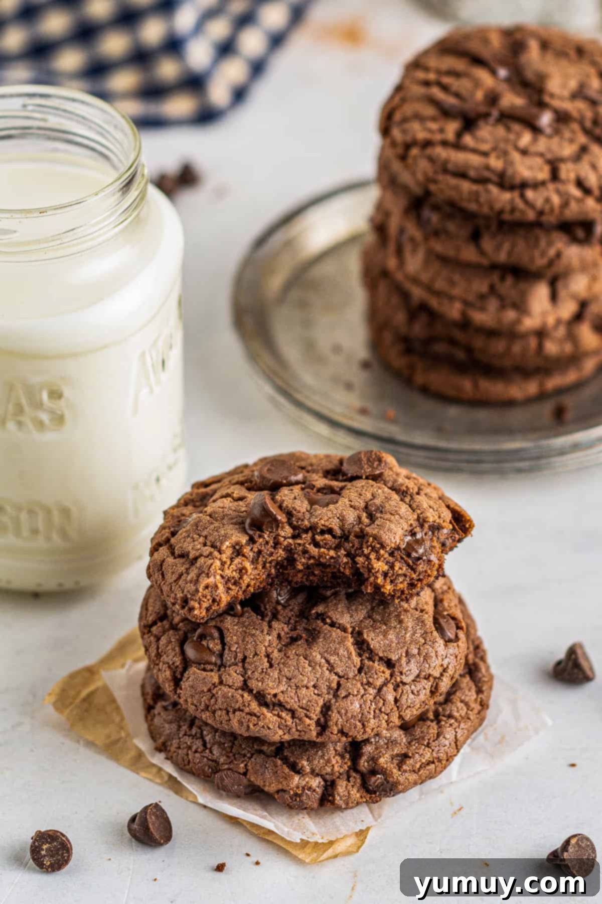 A tantalizing stack of chocolate cookies with a bite taken from the top one, revealing a soft, chewy interior filled with melted chocolate chips.