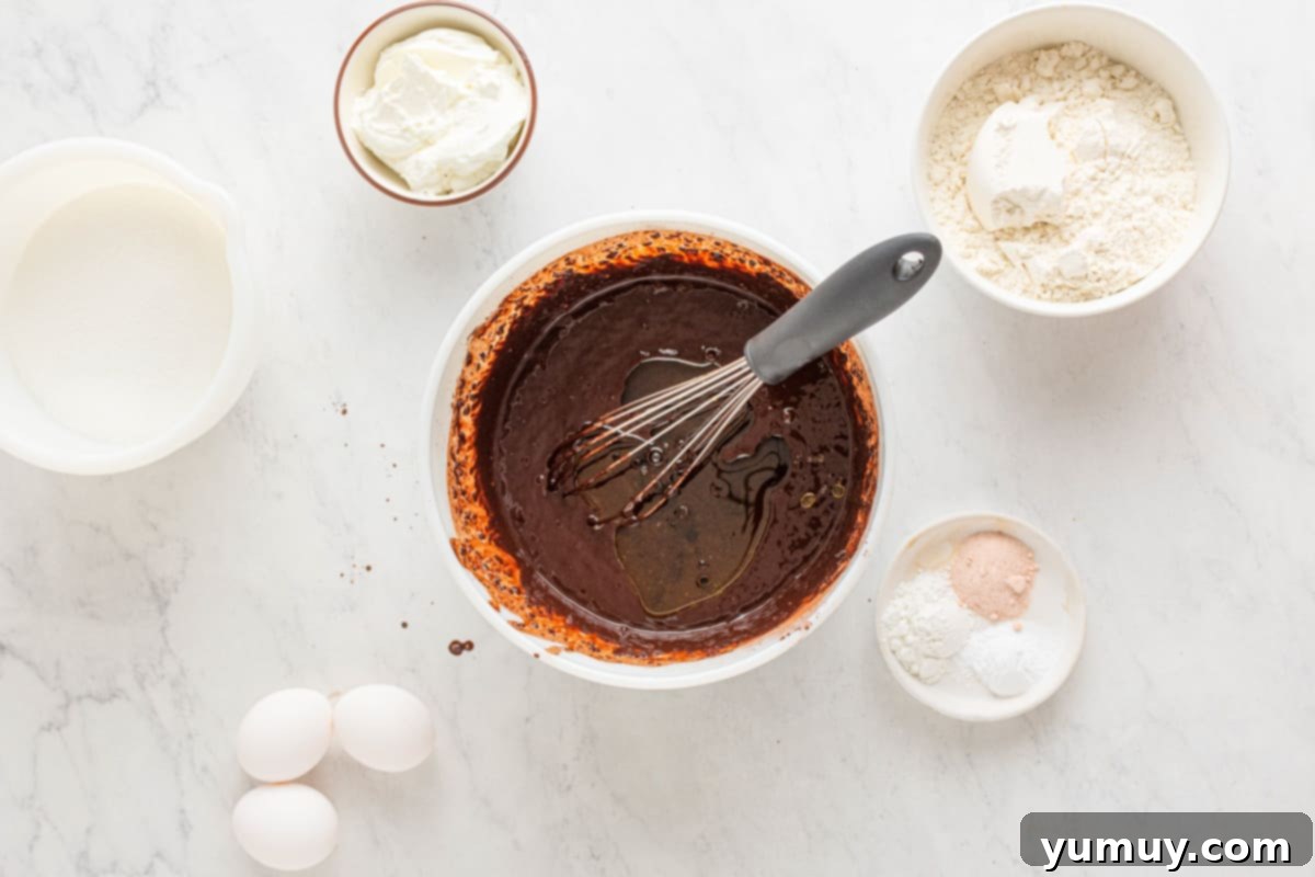 All the chocolate cake ingredients – cake mix, water, melted butter, and eggs – gathered in a large bowl, ready to be stirred into a smooth batter.
