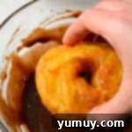Crispy Chocolate Cruller Twists 12 hand dipping a cruller into a bowl of chocolate glaze