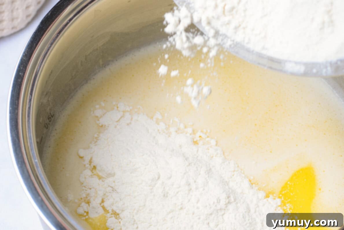 Crispy Chocolate Cruller Twists 15 adding flour to wet ingredients in a metal bowl