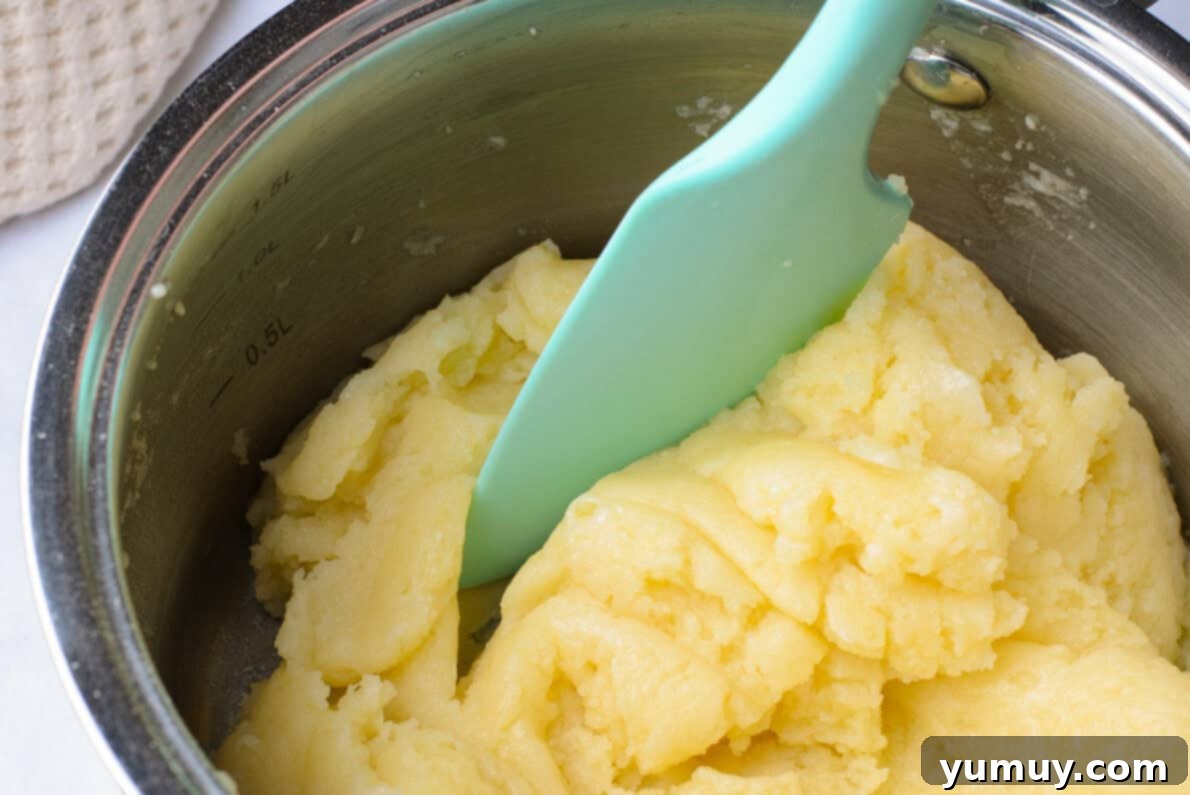 Crispy Chocolate Cruller Twists 16 cruller dough in a metal bowl with a blue spatula