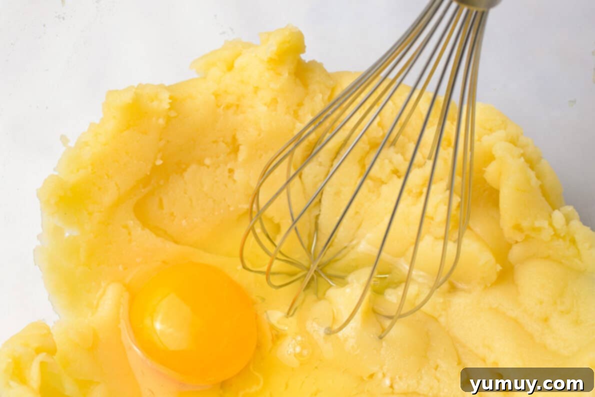 Crispy Chocolate Cruller Twists 17 using a whisk to incorporate an egg into the dough in a glass bowl