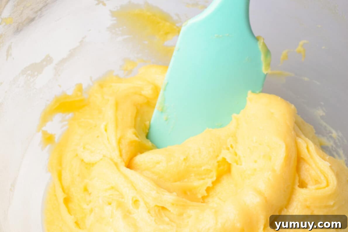 Crispy Chocolate Cruller Twists 18 cruller dough in a glass bowl with a blue spatula