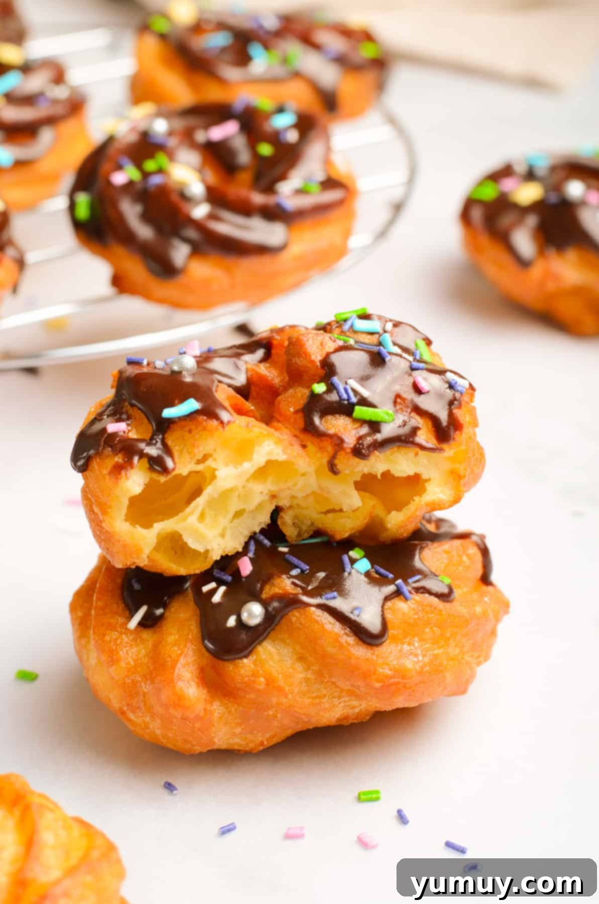 Crispy Chocolate Cruller Twists 3 stack of 2 chocolate glazed crullers with a bite taken from one