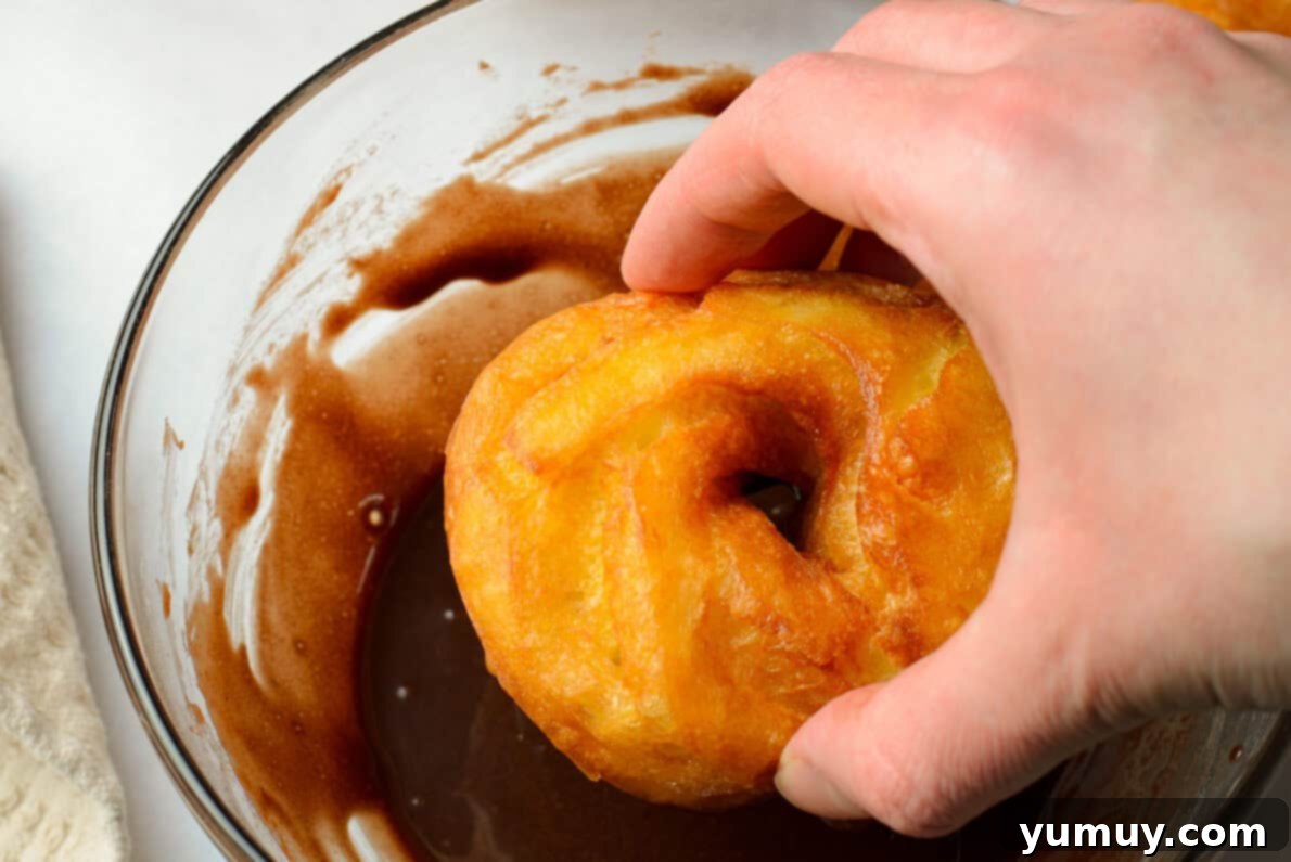Crispy Chocolate Cruller Twists 21 hand dipping a cruller into a bowl of chocolate glaze
