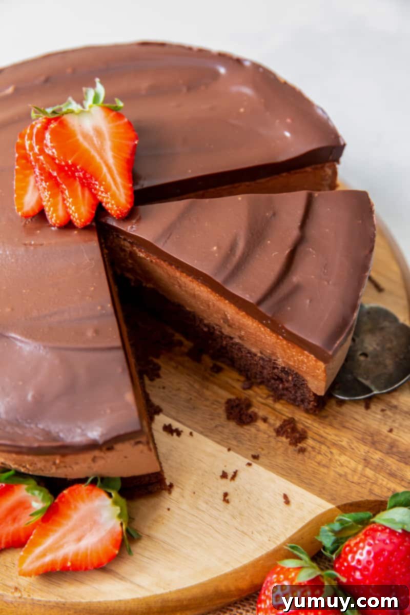 Decadent Chocolate Dream Cake 3 chocolate mousse cake on a wood serving board with a slice cut