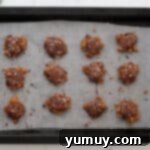 Irresistible Homemade Turtle Clusters 11 Finished chocolate and pecan turtle candies, garnished with crushed pecans, cooling on a baking sheet.