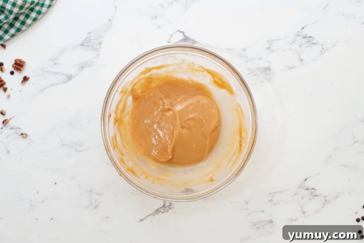 Irresistible Homemade Turtle Clusters 13 Melted caramel mixed with coconut oil, being stirred smoothly in a glass bowl.