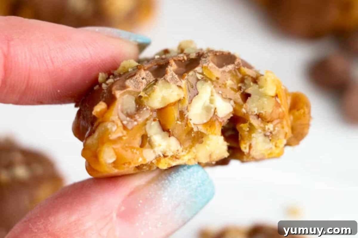 Irresistible Homemade Turtle Clusters 3 A hand holding a homemade turtle candy, bitten to reveal the layers of chewy caramel, crunchy pecans, and smooth chocolate.