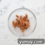 Irresistible Homemade Turtle Clusters 5 Unwrapped soft caramels sitting in a clear glass bowl, ready for melting.