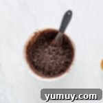 chocolate chips added to chocolate muffin batter in a white bowl with a whisk