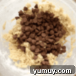 cookie dough dip with chocolate chips on top in a glass bowl.