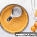 The process of pressing graham cracker crust mixture into the base and sides of a springform pan using a glass for an even layer.