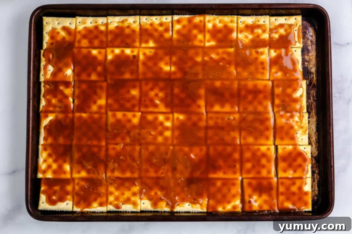 Yuletide Toffee Obsession 8 saltine crackers topped with caramel on a baking sheet.