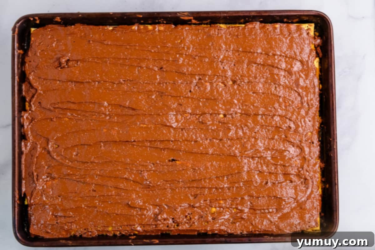 Yuletide Toffee Obsession 11 melted chocolate spread over saltine cracker toffee on a baking sheet.