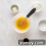 Golden Cinnamon Bundt Cake 6 whisked egg yolks in a white bowl with a whisk.